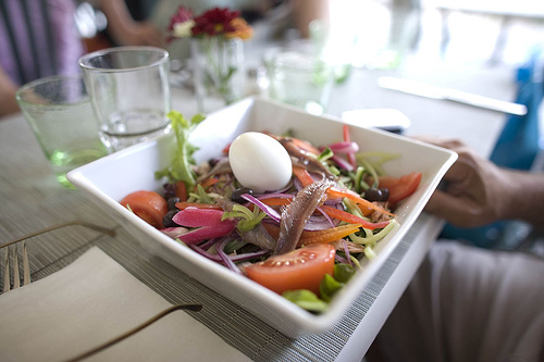 Photoreal photograph of the finished dish Salade niçoise, the actual plate from France, handmade ceramic, natural window light, shallow depth of field, no text, no logo, no people, Natural window light, ivory linen, handmade ceramic, shallow depth of field, no text, no logo, no watermark, fine-dining magazine photograph. Salade niçoise