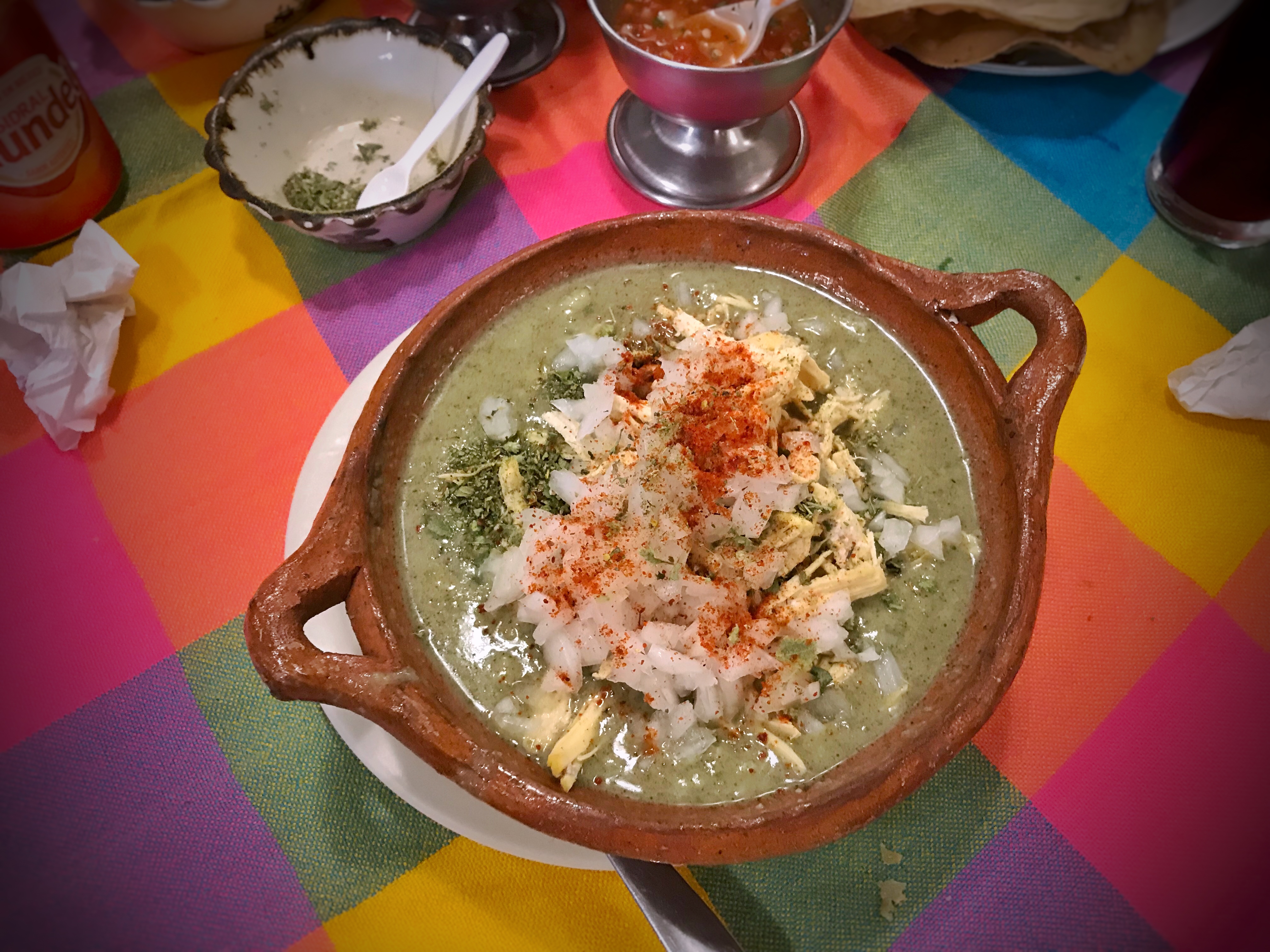 A bowl of green pozole with hominy, chicken, radish, cabbage, and lime, Natural window light, ivory linen, handmade ceramic, shallow depth of field, no text, no logo, no watermark, fine-dining magazine photograph. Green Pozole