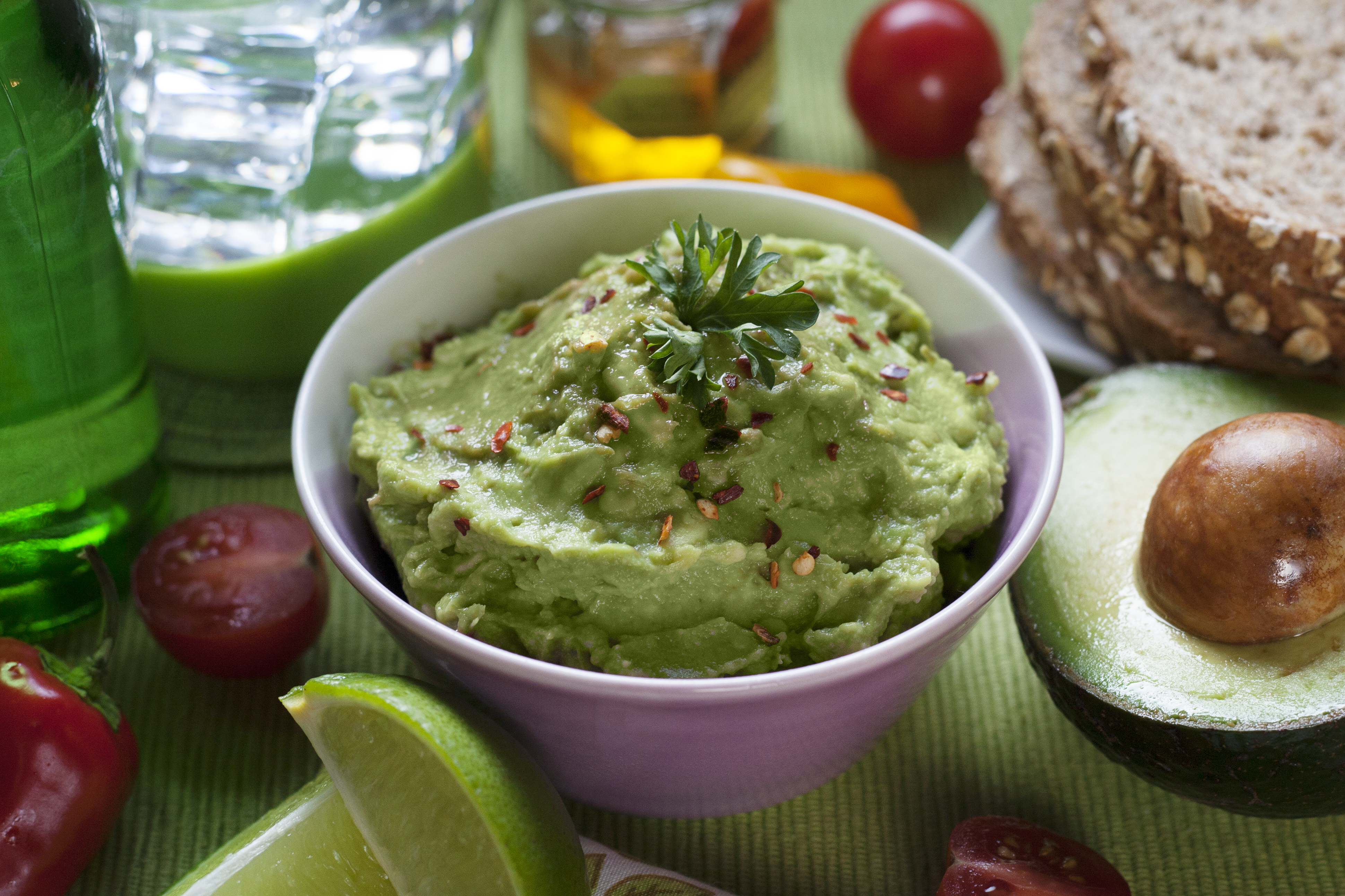 A stone bowl of chunky guacamole with lime and cilantro, Natural window light, ivory linen, handmade ceramic, shallow depth of field, no text, no logo, no watermark, fine-dining magazine photograph. Lime Guacamole
