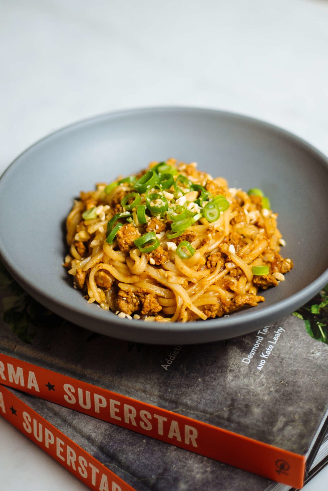 Photoreal photograph of the finished dish Shan noodles (ရှမ်းခေါက်ဆွဲ), the actual plate from Myanmar, handmade ceramic, natural window light, shallow depth of field, no text, no logo, no people, Natural window light, ivory linen, handmade ceramic, shallow depth of field, no text, no logo, no watermark, fine-dining magazine photograph. Shan noodles